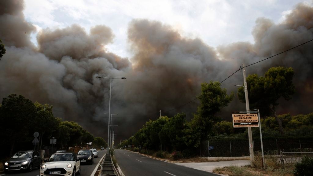 Smoke rise over an avenue during a forest fire in Neo Voutsa a northeast suburb of Athens Greece on Monday